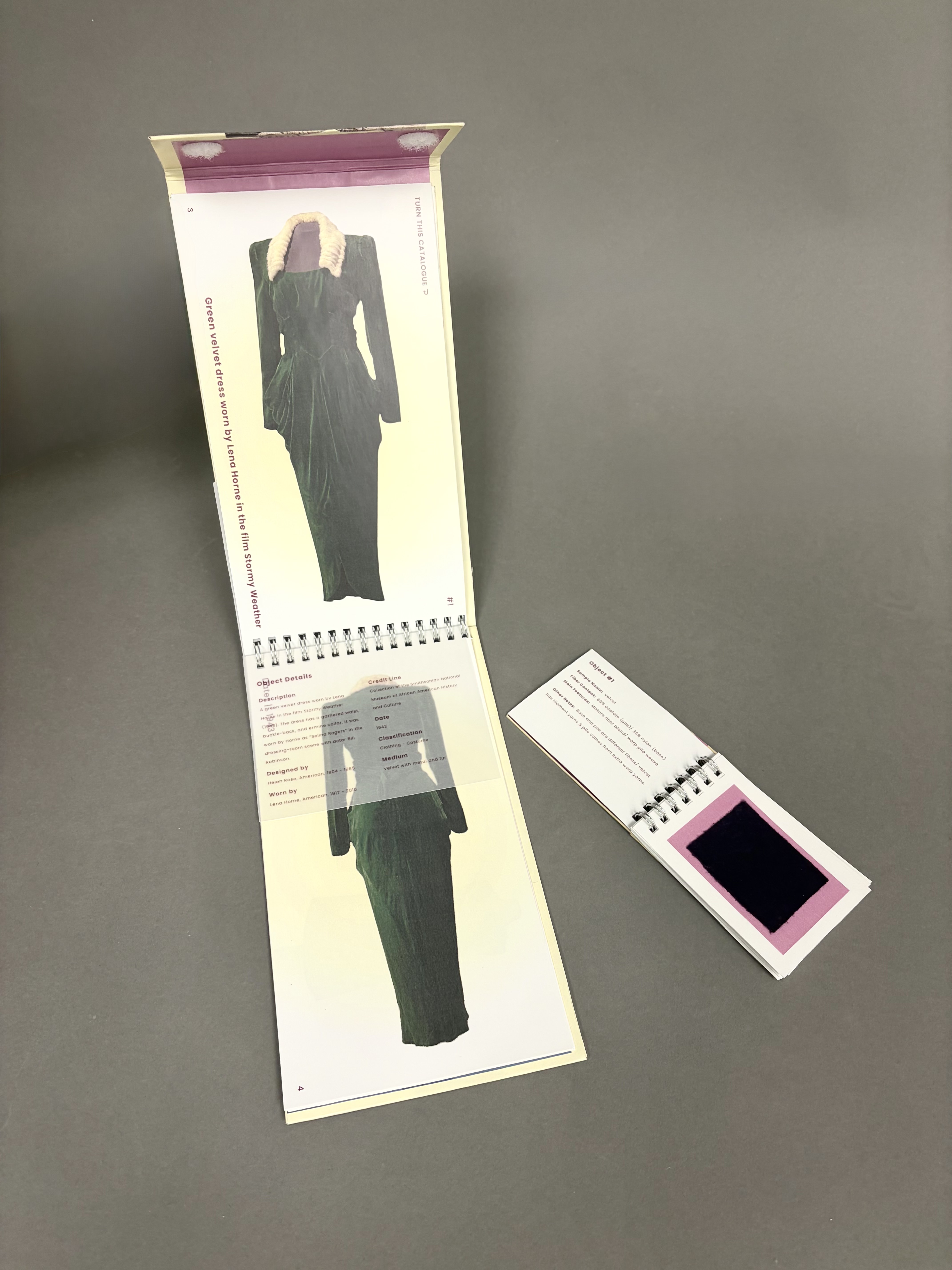 The open book next to the open mini textile handbook, showcasing a dress and its textile.